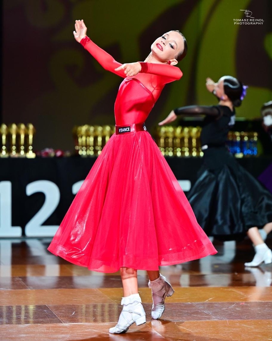 Młoda tancerka Dance Factory w czerwonej sukni na turnieju tańca standardowego